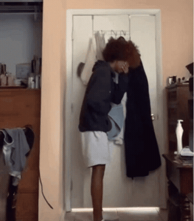 Person Standing In Front Of Door With Clothes Hanging GIF