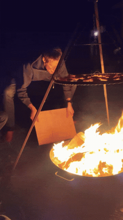 Person Standing In Front Of Fire With Cardboard Box GIF