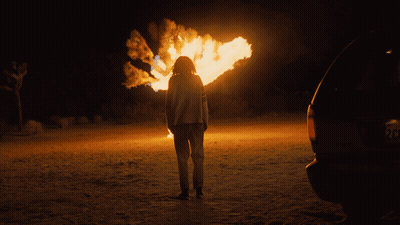Person Standing In Front Of Fire With License Plate Saying RC GIF