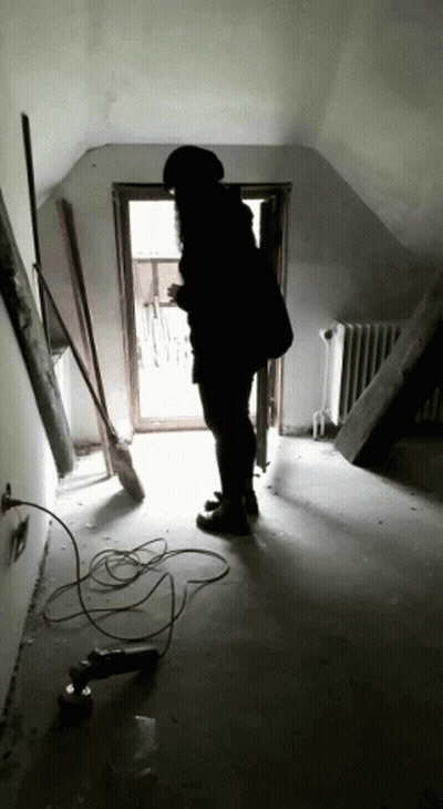 Person Standing In Hallway With Broom And Drill GIF