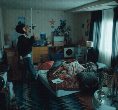 Person Standing In Room With Posters And Bed GIF