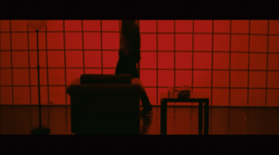 Person Standing On Couch In Front Of Red Screen GIF