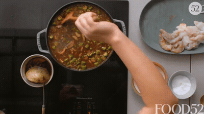 Person Stirring Pot With Wooden Spoon In Front Of Shrimp GIF