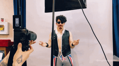 Person Taking Picture Of Man In Vest And Sunglasses GIF