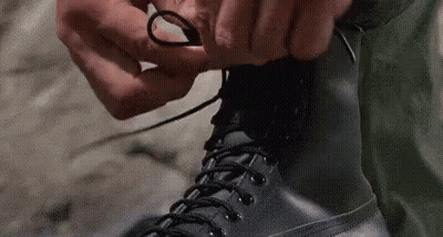 Person Tying Boots On Sidewalk GIF