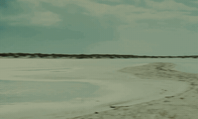 Person Walking Beach With Boat GIF