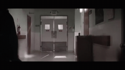 Person Walking Down Hospital Hallway With Exit Sign GIF