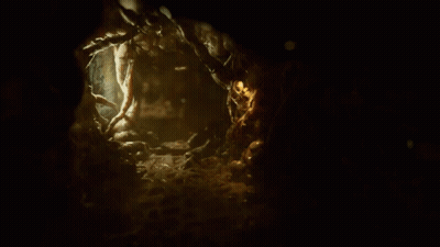 Person Walking In Dark Cave With Green Light On Chest GIF