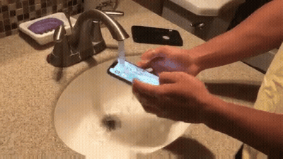 Person Washing Hands While Holding Phone GIF
