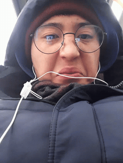 Person Wearing Glasses And Earbuds Looking Down GIF