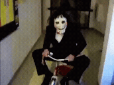 Person Wearing Puppet Mask Riding Bicycle In Hallway GIF