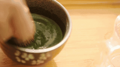 Person Whisking Bowl Of Green Liquid With Brush GIF
