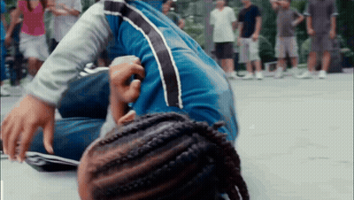 Person With Braids Lying On Ground As People Watch GIF