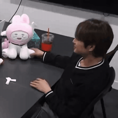 Person With Stuffed Animal And Drink At Table GIF