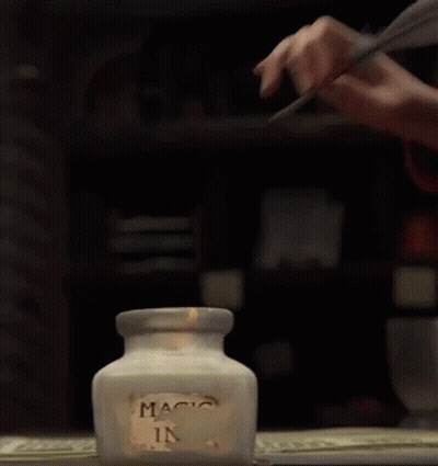 Person Writing With Feather In Magic Ink Jar GIF
