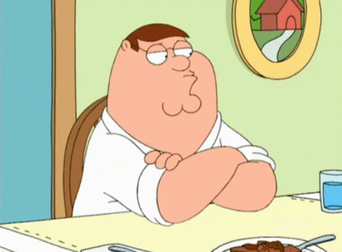 Peter Griffin Sits At A Table With His Arms Crossed GIF