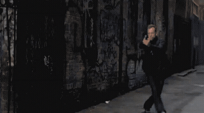 Pixelated Man Holding Gun In Front Of Graffiti Wall GIF