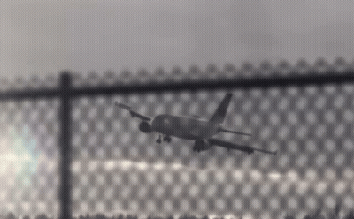 Plane Flying Over Chain Link Fence GIF