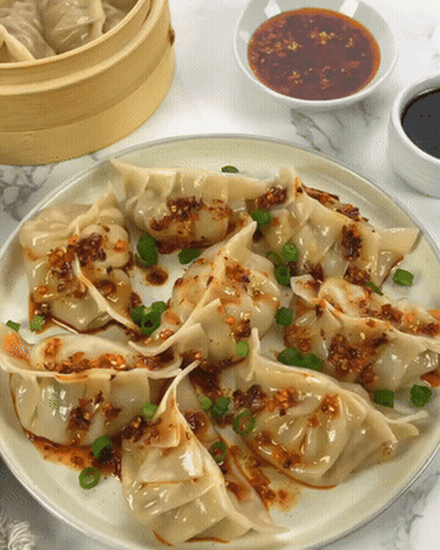 Plate Of Dumplings With Green Onions And Sauce GIF