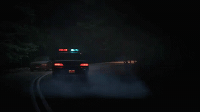 Police Car Driving Down Dark Road GIF