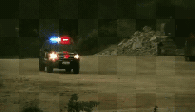 Police Car With Lights On Dirt Road GIF