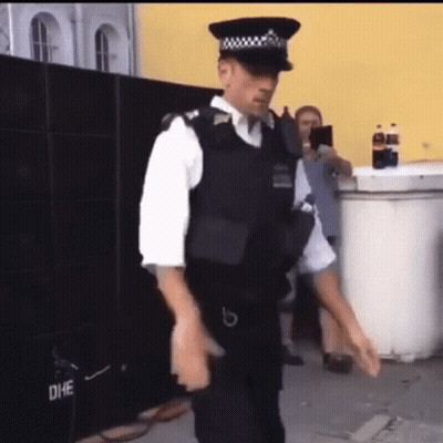 Police Officer Dancing In Front Of Yellow Building GIF