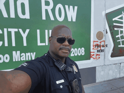 Police Officer Selfie With Green Kid Row Sign GIF
