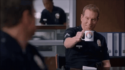 Police Officer Sitting at Desk Holding Police Department Mug