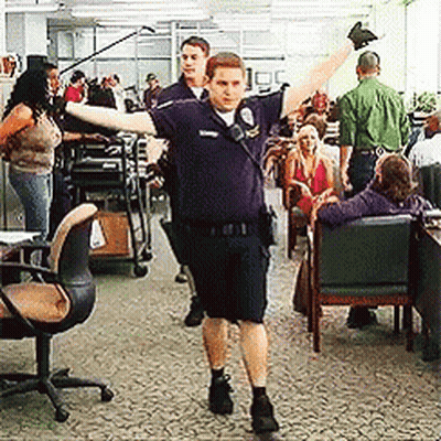 Police Officer Standing With Arms Outstretched In Crowded Room GIF