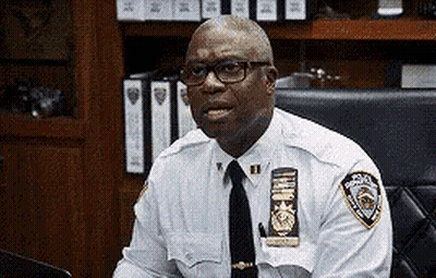 Police Officer With Glasses And Tie Sitting GIF