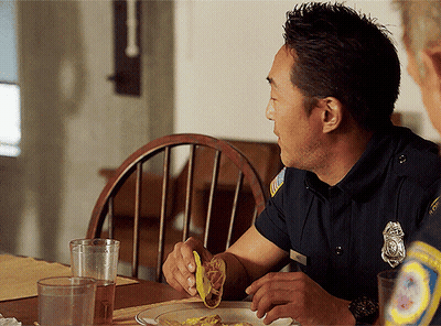 Policeman Eating Taco At Table GIF
