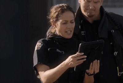 Policewoman Looking At Tablet With Man Behind GIF