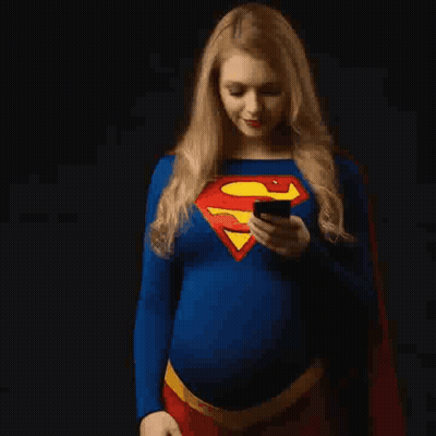 Pregnant Woman Dressed As Superman Looking At Phone GIF