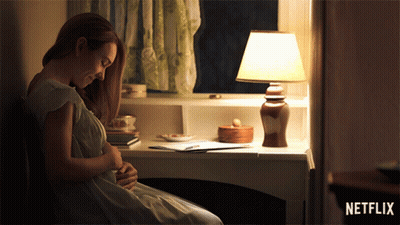 Pregnant Woman Sitting At Desk With Lamp And Netflix Logo GIF