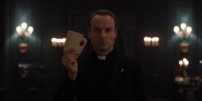 Priest Holding Paper With Cross On Jacket GIF