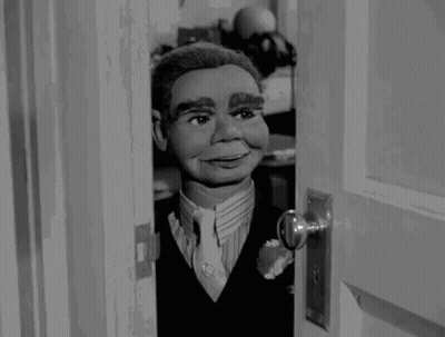 Puppet In Suit Looking Out Doorway GIF