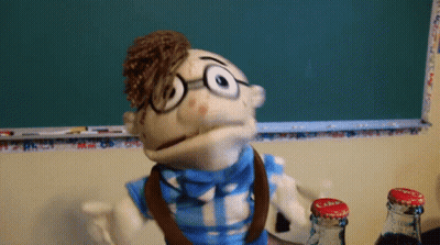 Puppet With Glasses And Bow Tie In Front Of Chalkboard GIF