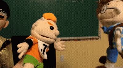 Puppet With Letter T Talking To Another Puppet GIF