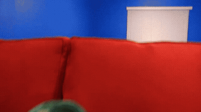 Puppet With Open Mouth On Red Couch GIF