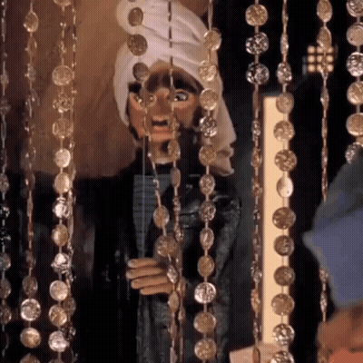 Puppet With Turban Hanging From Gold Beads GIF