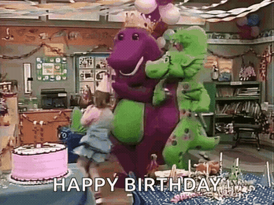 Purple And Green Dinosaur Standing Next To Birthday Cake GIF