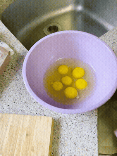 Purple Bowl Filled With Yellow Eggs Beside Sink GIF