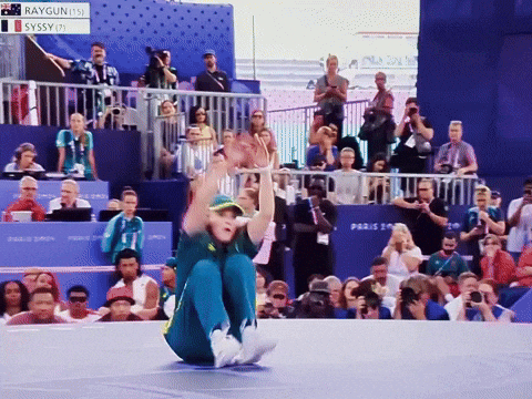 Raygun Is Sitting On The Floor In Front Of A Large Crowd GIF