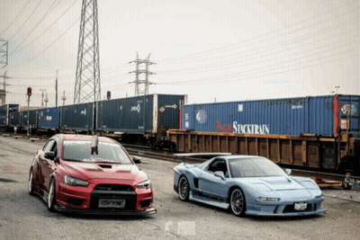 Red And Blue Cars In Front Of Stocktrain Container GIF
