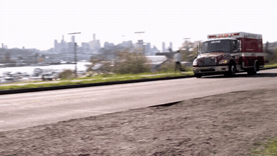 Red And White Ambulance Driving Down City Street GIF