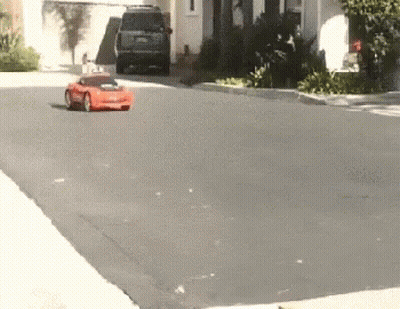 Red Car Driving Down Street Next To House GIF
