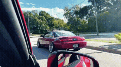 Red Car Driving Down Street With License Plate Saying Ecr GIF