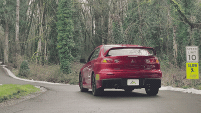 Red Car Driving Past Speed Limit Sign GIF