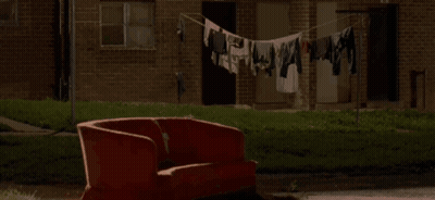 Red Couch By Brick Building With Clothes Line GIF