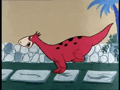 Red Dinosaur Standing Next to Stone Wall
